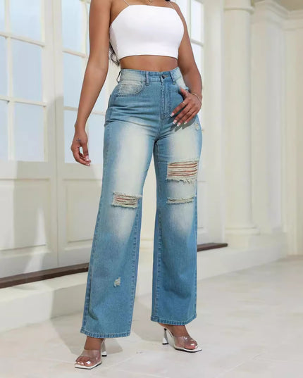 Person wearing high-waisted, distressed blue jeans and a white top indoors.