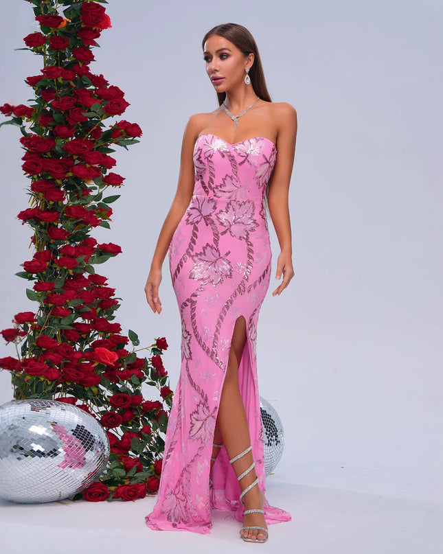 Woman in a pink evening gown standing next to a decorative arrangement of red roses and a disco ball on a light gray background.