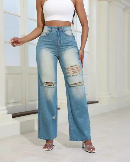 Person wearing light blue distressed jeans and a white top in a bright indoor setting.
